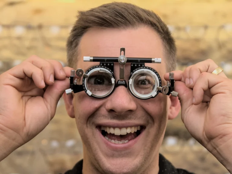 Junger Mann trägt eine Messbrille mit Lächeln, hält die Messbrille in den Händen.