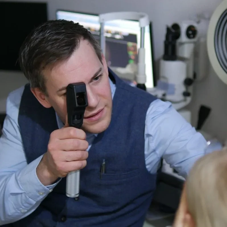 Optiker untersucht das Auge einer Patientin mit einem Skiaskop.